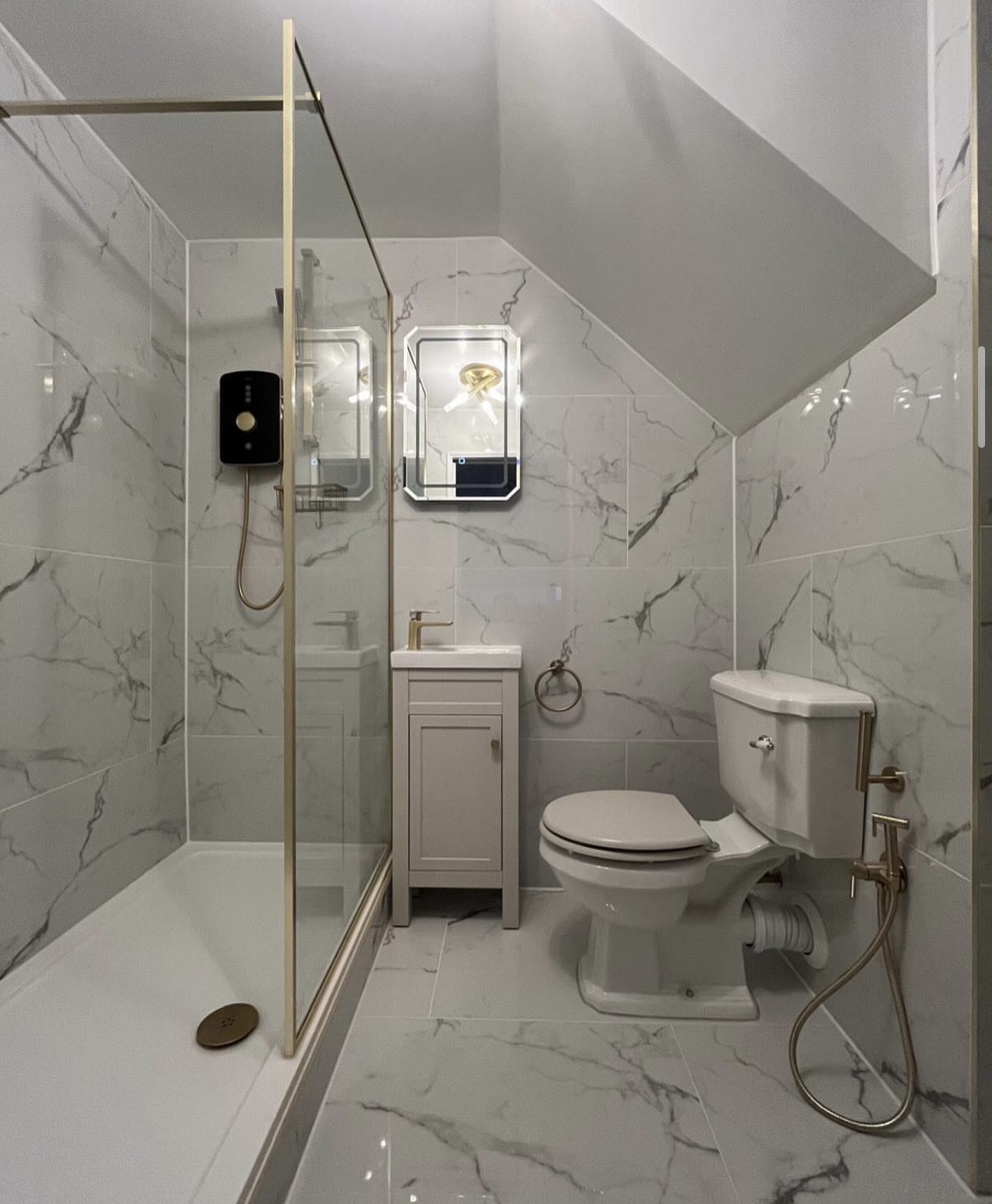 Marble loft bathroom with walk-in shower and gold trim by M3 Trades