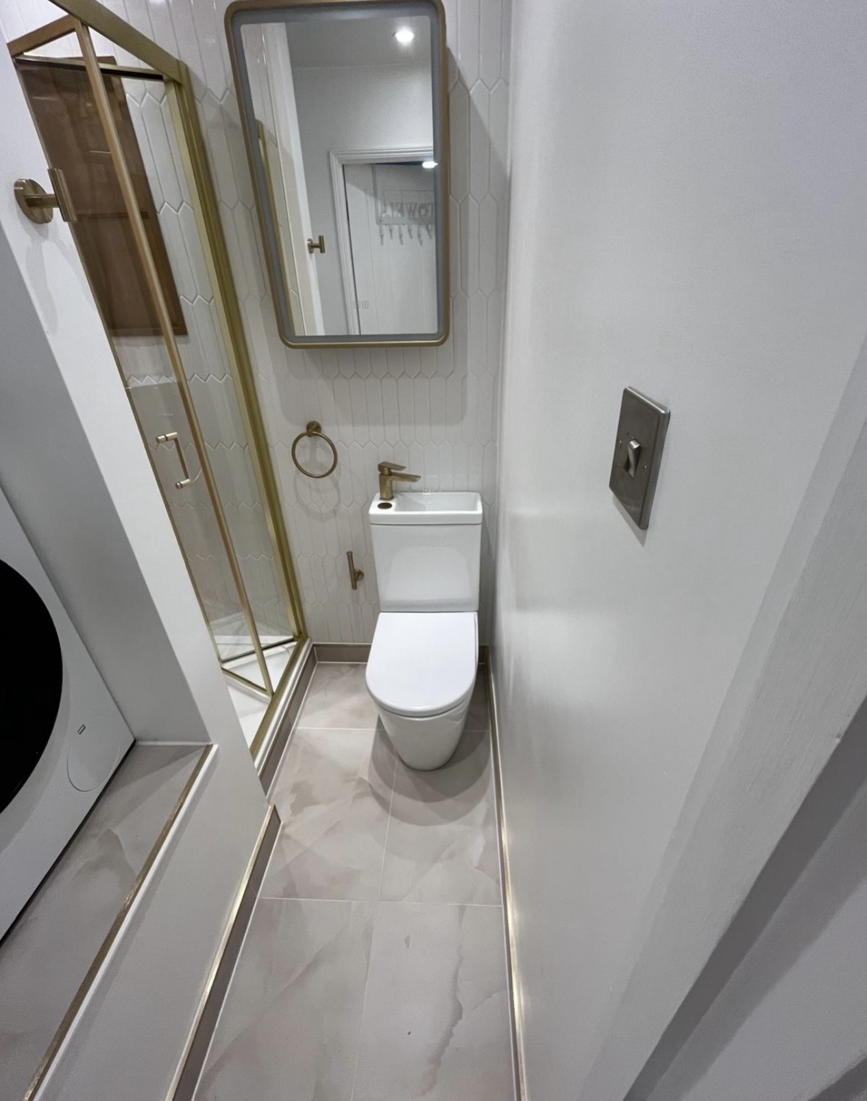 Space-saving WC with brushed brass tap and framed mirror in a Birmingham upstairs bathroom by M3 Trades