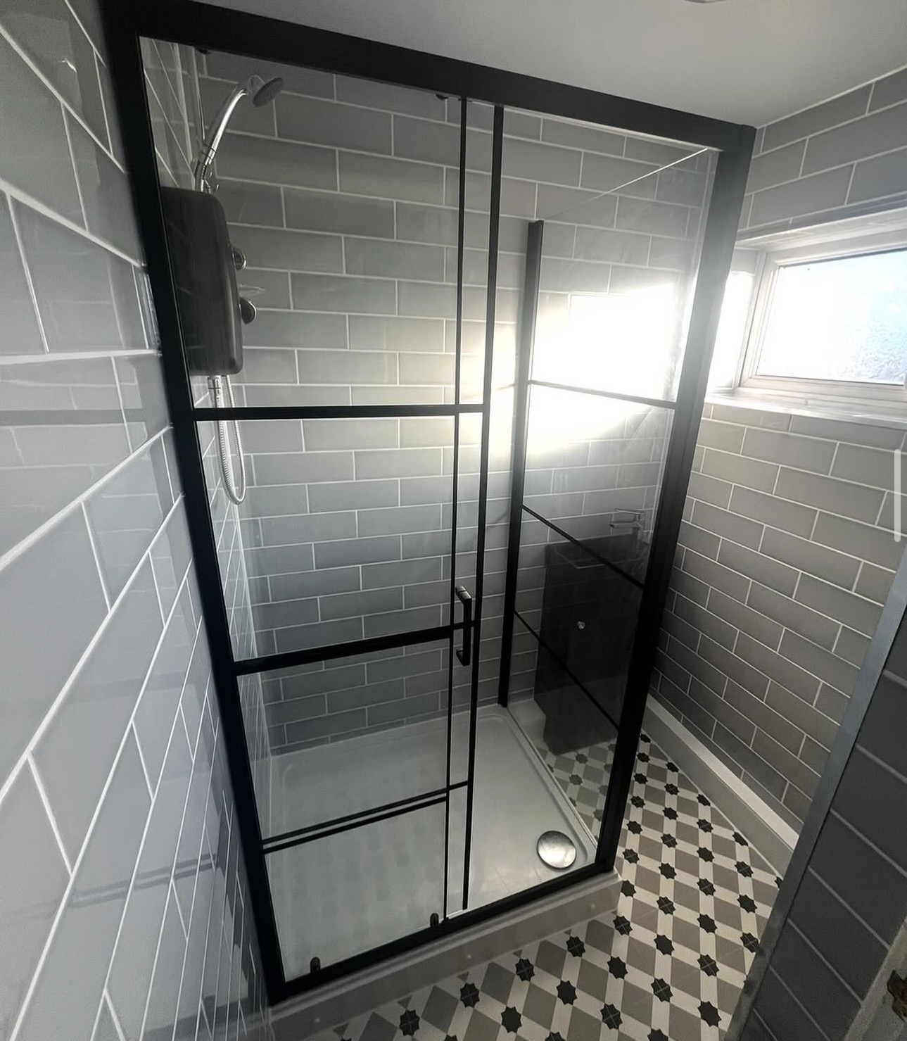 Black framed shower enclosure with metro tiles and patterned floor by M3 Trades