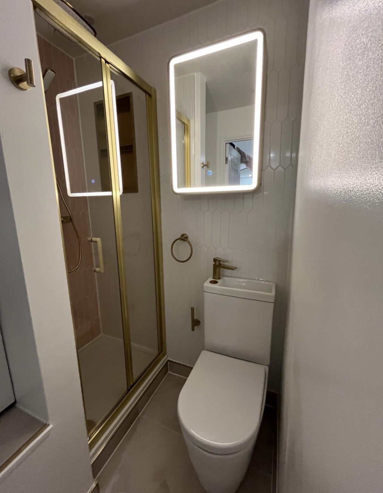 Brushed brass shower enclosure with LED mirror and space-saving WC basin combo in a Birmingham utility bathroom by M3 Trades