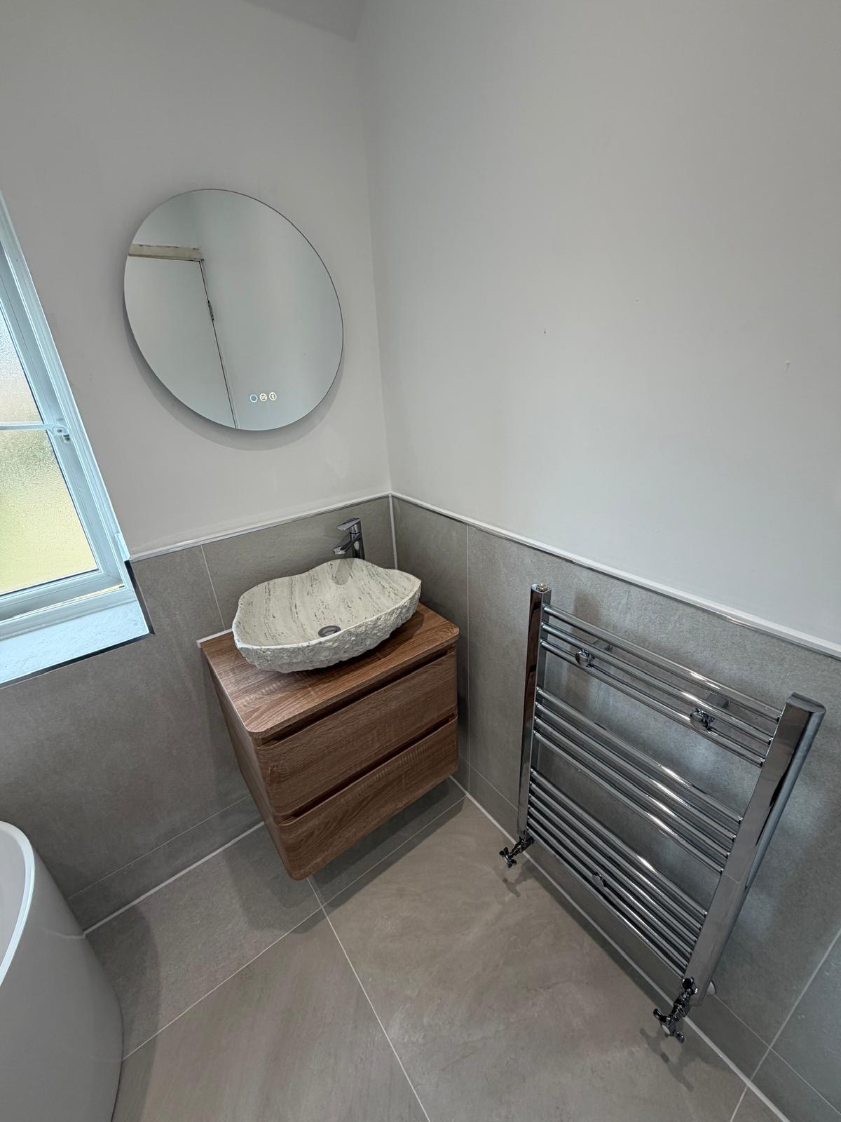 Walnut floating vanity with natural stone vessel basin, LED round mirror and chrome heated towel rail in Rubery Birmingham by M3 Trades